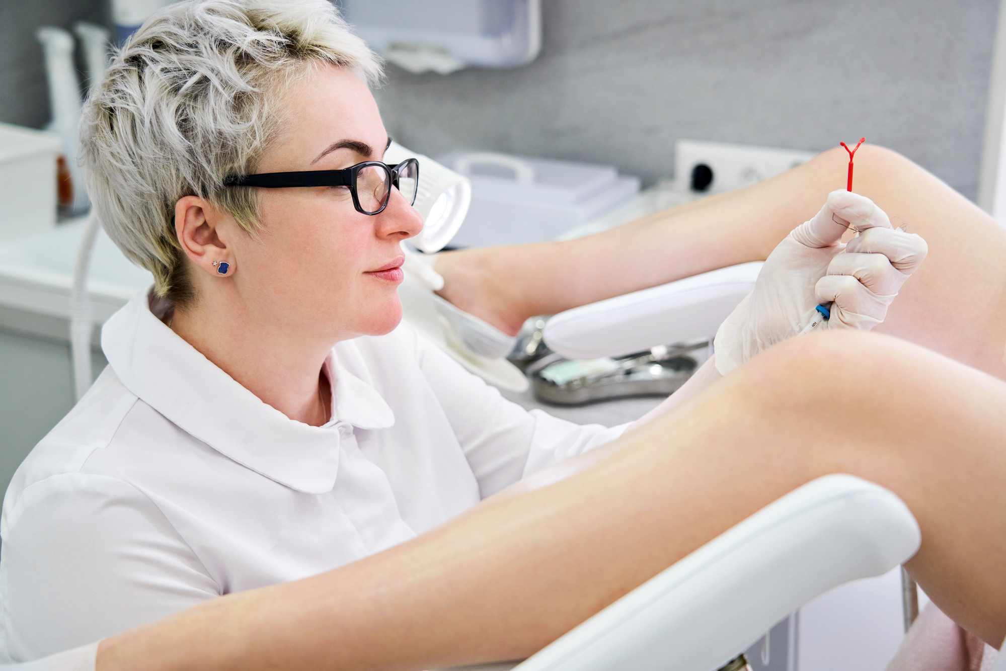 A healthcare provider preparing to insert an IUD during a gynaecological exam.
